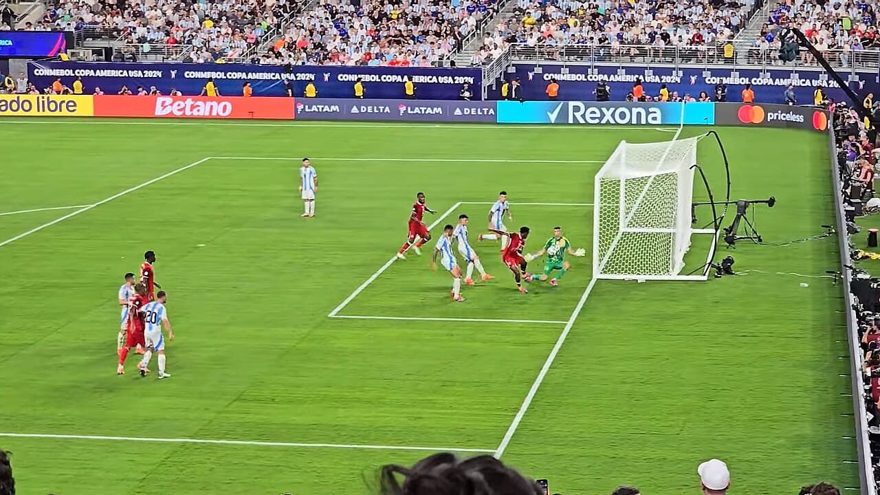 Emiliano Martínez dives at the feet of Jonathan David during Argentina against Canada at the 2024 Copa América