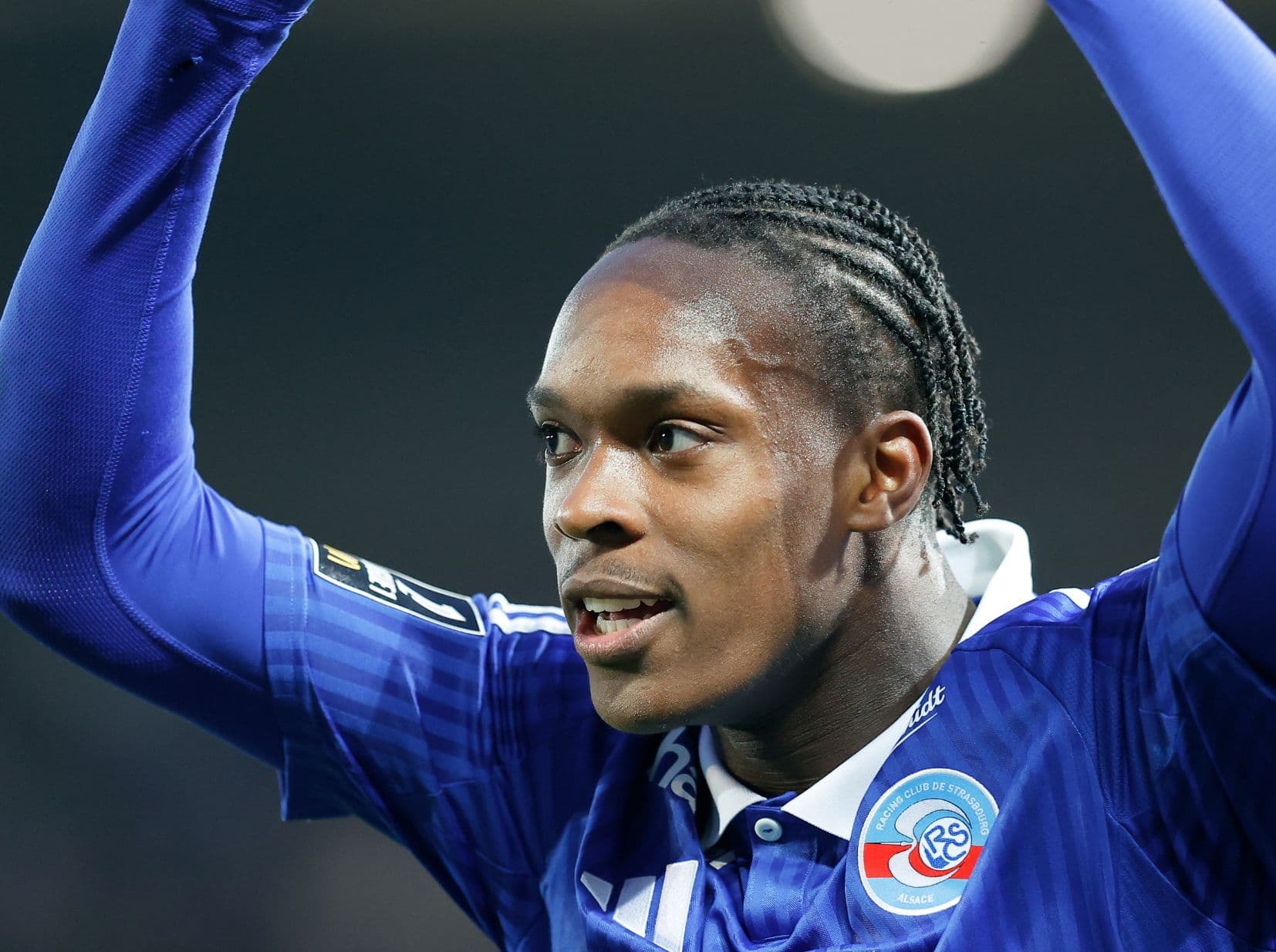 Emanuel Emegha raises both arms to acknowledge Strasbourg supporters