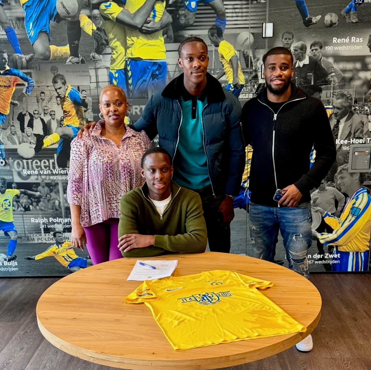 Joshua Emegha signs for FC Lisse with members of the Emegha family standing behind him